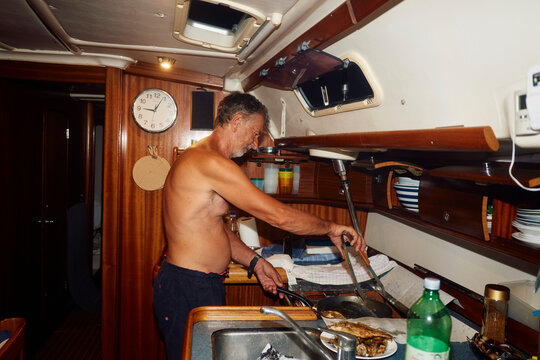 Man prepares dinner in the cabin of a boat