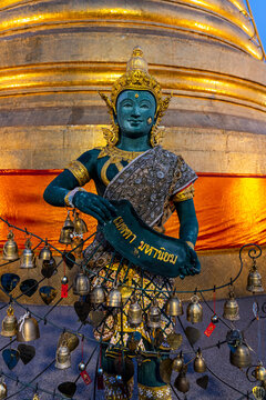 Green deity statue and prayer bells at the base of the golden stupa at Wat Saket in Bangkok