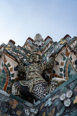 Fototapeta premium Intricate porcelain mosaics and Yaksha demon guardian on the tiered Prang of Wat Arun, Bangkok