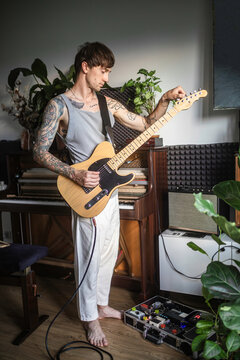 A musician tunes a bass guitar at home