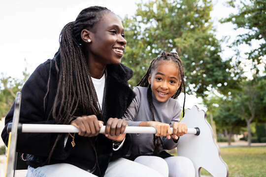 A mother and her daughter on the spring rider in the park