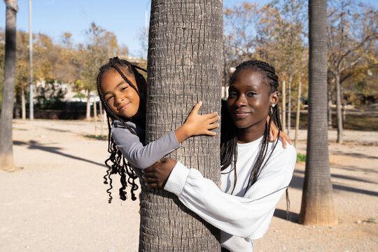 Mother and daughter hugging a tree