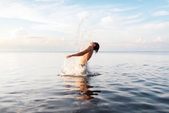 teenage boy jumping out of water