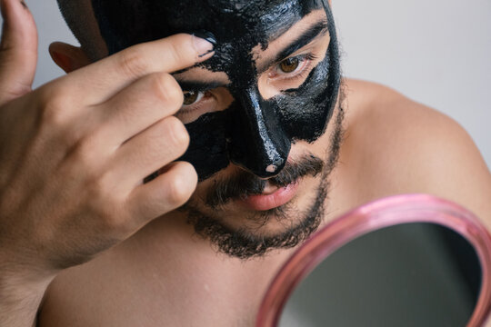Man applying charcoal face mask 