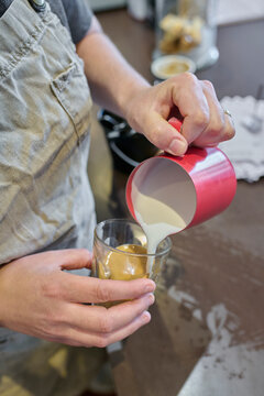 Pouring Milk Over Espresso in a Cozy Coffee Shop Setting