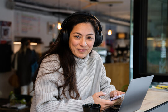 A woman smiling while working with a computer at a coffee shop