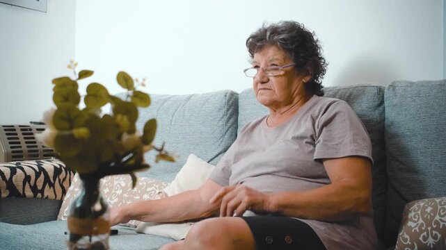 Portrait mature woman with remote controller switches channels on TV and watching comedy movie show serial enjoying leisure time at home alone Fun weekend time