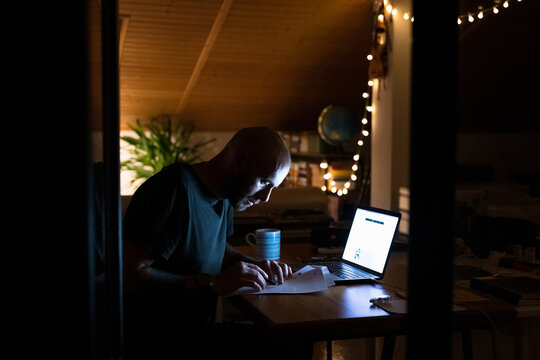 Man working late with laptop and papers