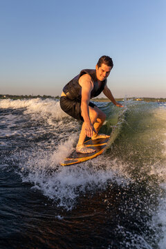 Man on wakesurf in sunset light.