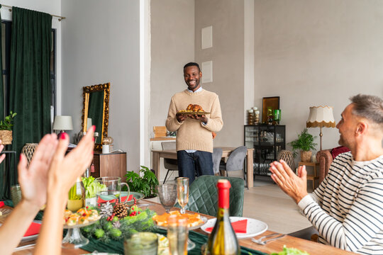 Applauses for man bringing baked chicken at Christmas celebration