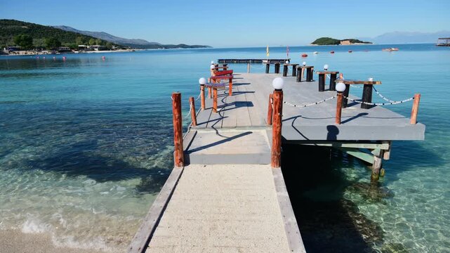 Serene seaside scene with a wooden pier extending into clear turquoise water in Ksamil