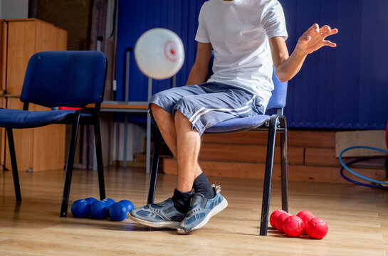 Faceless Paralympic athlete throws ball during boccia training