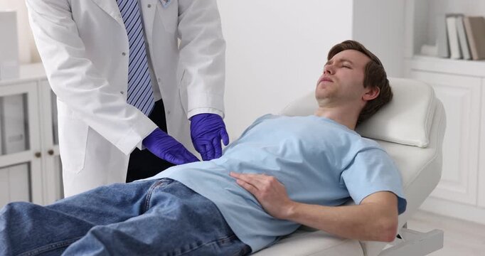 Urologist in protective gloves examining patient on medical couch in clinic, closeup
