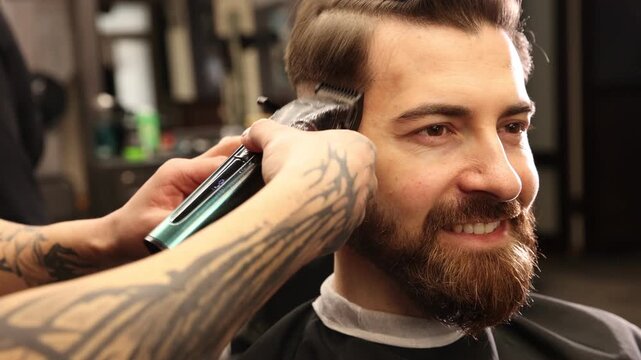 Stylist cutting man's hair with clipper in barbershop, closeup