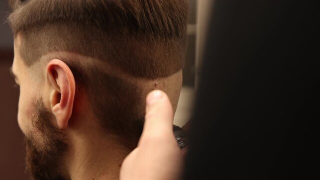 Stylist cutting man's hair with clipper in barbershop, closeup