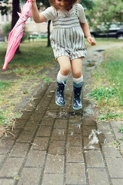 Girl is jumping on the puddles.
