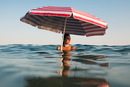 Relaxed woman under beach umbrella in the water