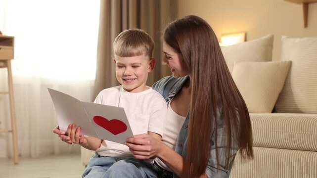 Mother's Day. Happy woman with her son and handmade greeting card at home