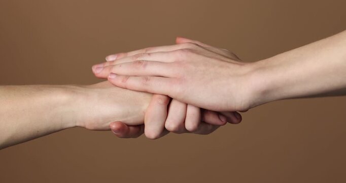 Woman holding man's hand on brown \background, closeup