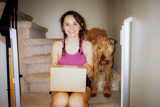 Woman with package on a stairway with dog beside her 