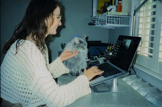 Woman working from home office with cat beside her 