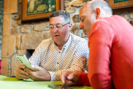Two businessmen using mobile phone in restaurant