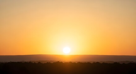 Obraz premium The sun sets over a serene landscape with a vibrant orange sky