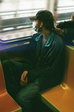 Young Man Sits on Subway with Mask