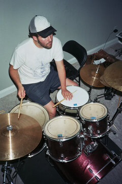 Man Sits at Drum Set