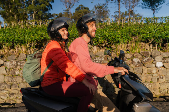 Man and woman traveling by scooter on tea plantation 