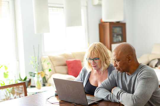 Senior couple at home living room checking finance on laptop 