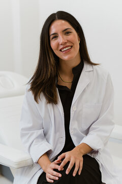 Smiling doctor wearing lab coat sitting in medical office