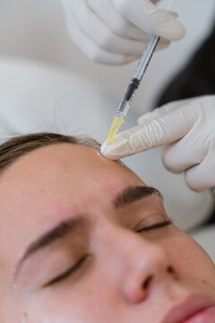 Doctor injecting botulinum toxin into patient's forehead