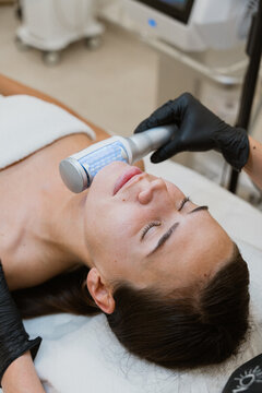 Beautician performing led light therapy treatment on woman's face