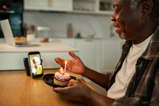 Senior man celebrating birthday over video call in home kitchen