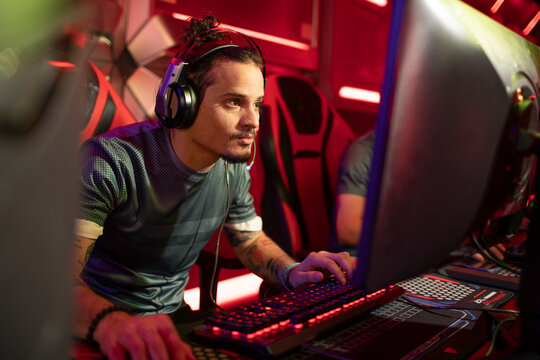 Focused gamer wearing headset playing on pc in esports arena