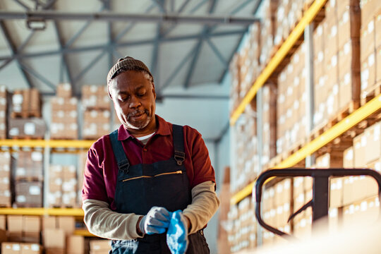 Warehouse worker putting on gloves in distribution center