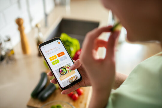 Woman using healthy meal planning app in kitchen
