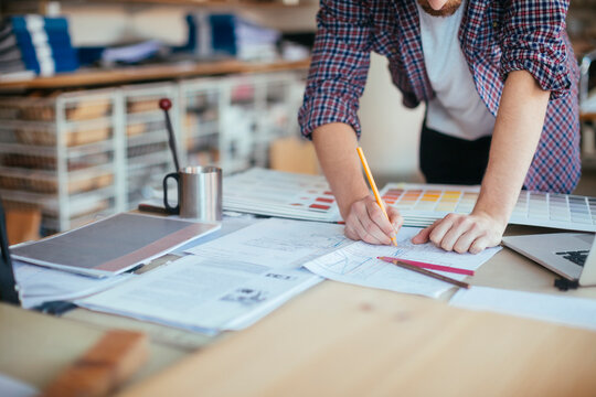 Designer drafting plans with color swatches in studio