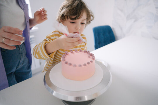 Kid helping his mother to decorate a cake