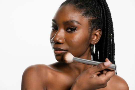 A woman puts blush on her face