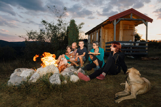 Family with a Dog Snacking by a Campfire