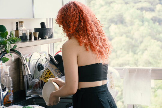 Curly readhead woman cleanning dishes