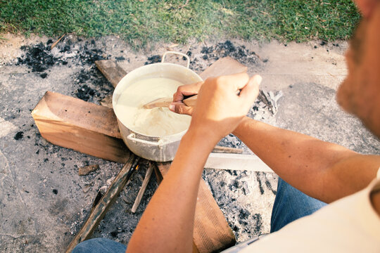 stirring the contents of a pot over firewood