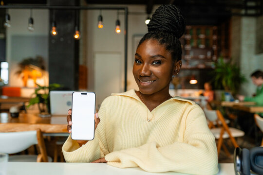 A woman shows a mobile phone with white screen