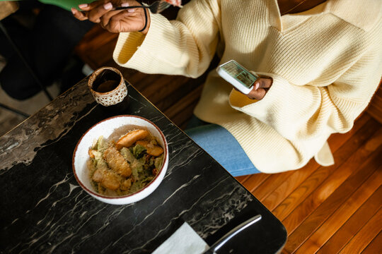 A woman uses a mobile phone in a cafe