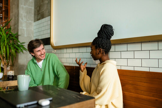 A man and a woman are talking in a cafe