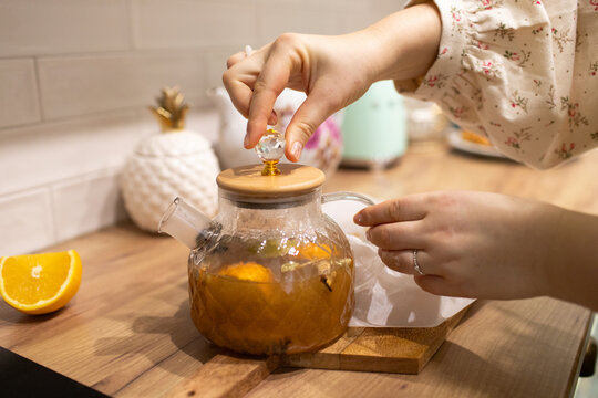 a woman prepares hot lemonade in a kettle