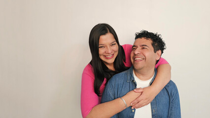 Fototapeta premium Latino man and woman in their 40s show their love to celebrate Valentine's Day and their anniversary with kisses and hugs, laughing and smiling