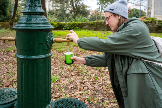 Woman filling water at fountain